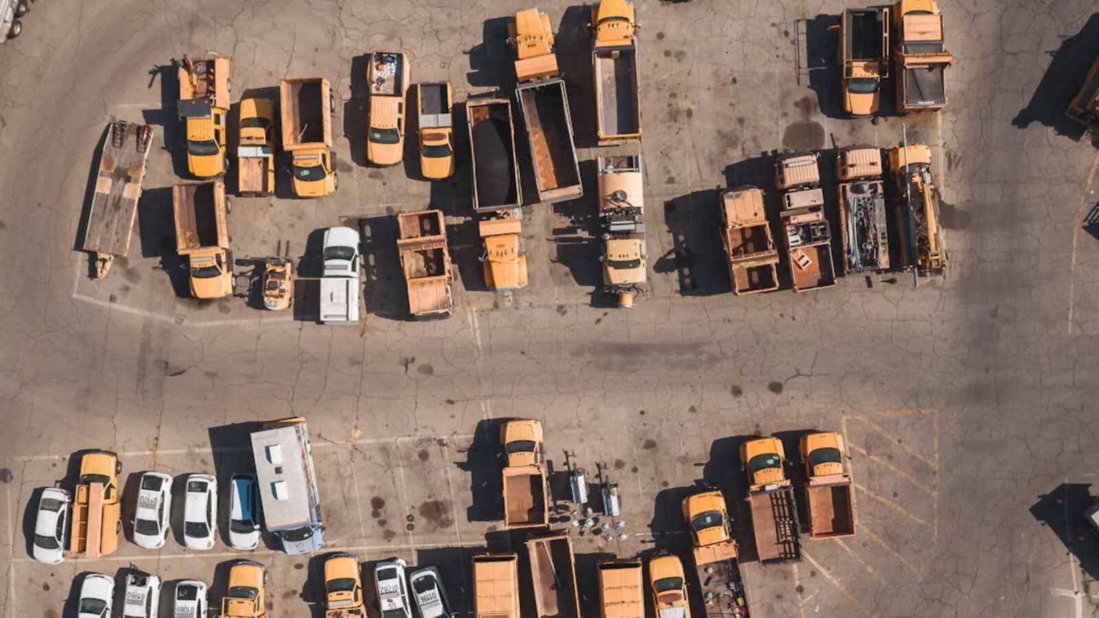 Выкуп авто в лизинге в Санкт-Петербурге — Top-down aerial view of various parked utility and service vehicles in a large industrial parking lot.