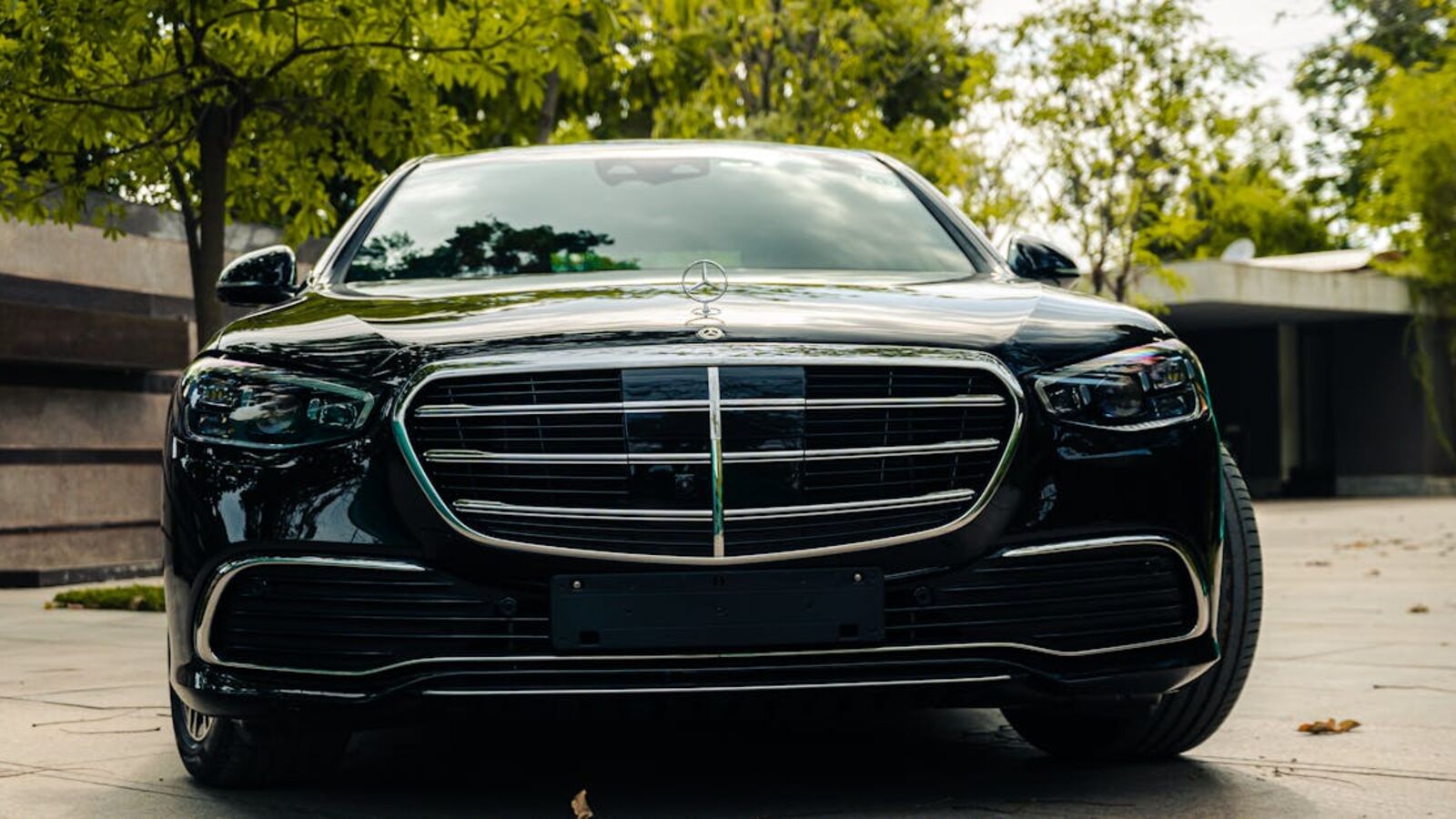 Кейс: срочная продажа кредитного автомобиля в Санкт-Петербурге — Front view of a luxurious black Mercedes Benz parked in a serene outdoor setting.