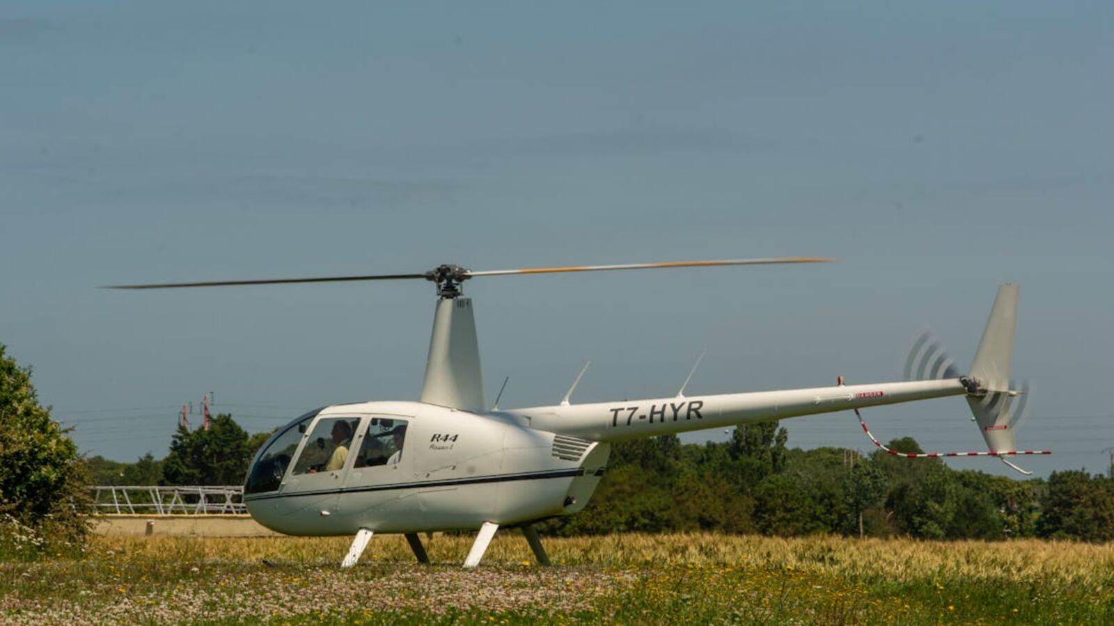 Кейс: продажа корпоративного вертолёта с документальной сложностью в Санкт-Петербурге — White helicopter standing on a grassy field on a sunny day with clear skies.