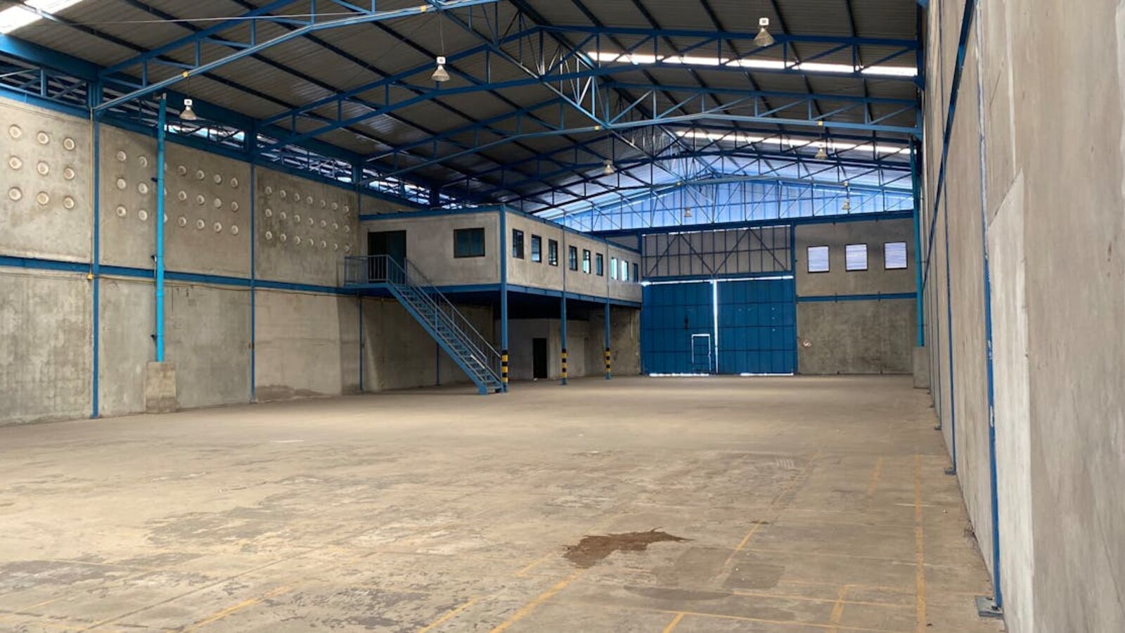 Кейс: продажа склада в срочном сценарии в Санкт-Петербурге — Empty warehouse with blue steel frame and concrete walls in Bangkok.