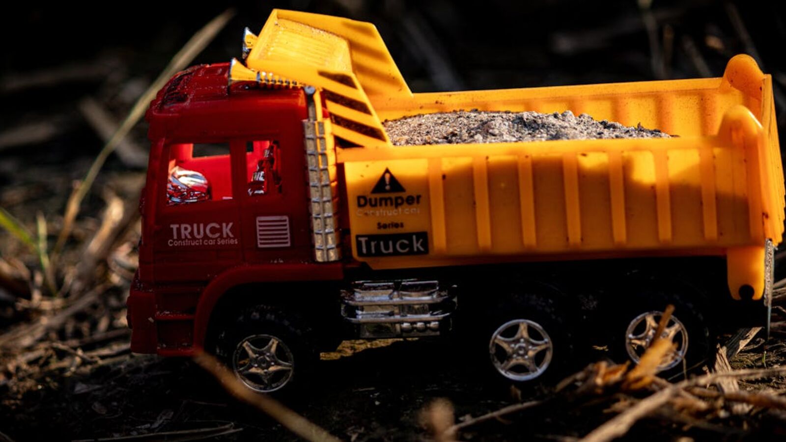Выкуп самосвалов в Санкт-Петербурге — A vibrant toy dump truck filled with gravel, captured outdoors in natural lighting.
