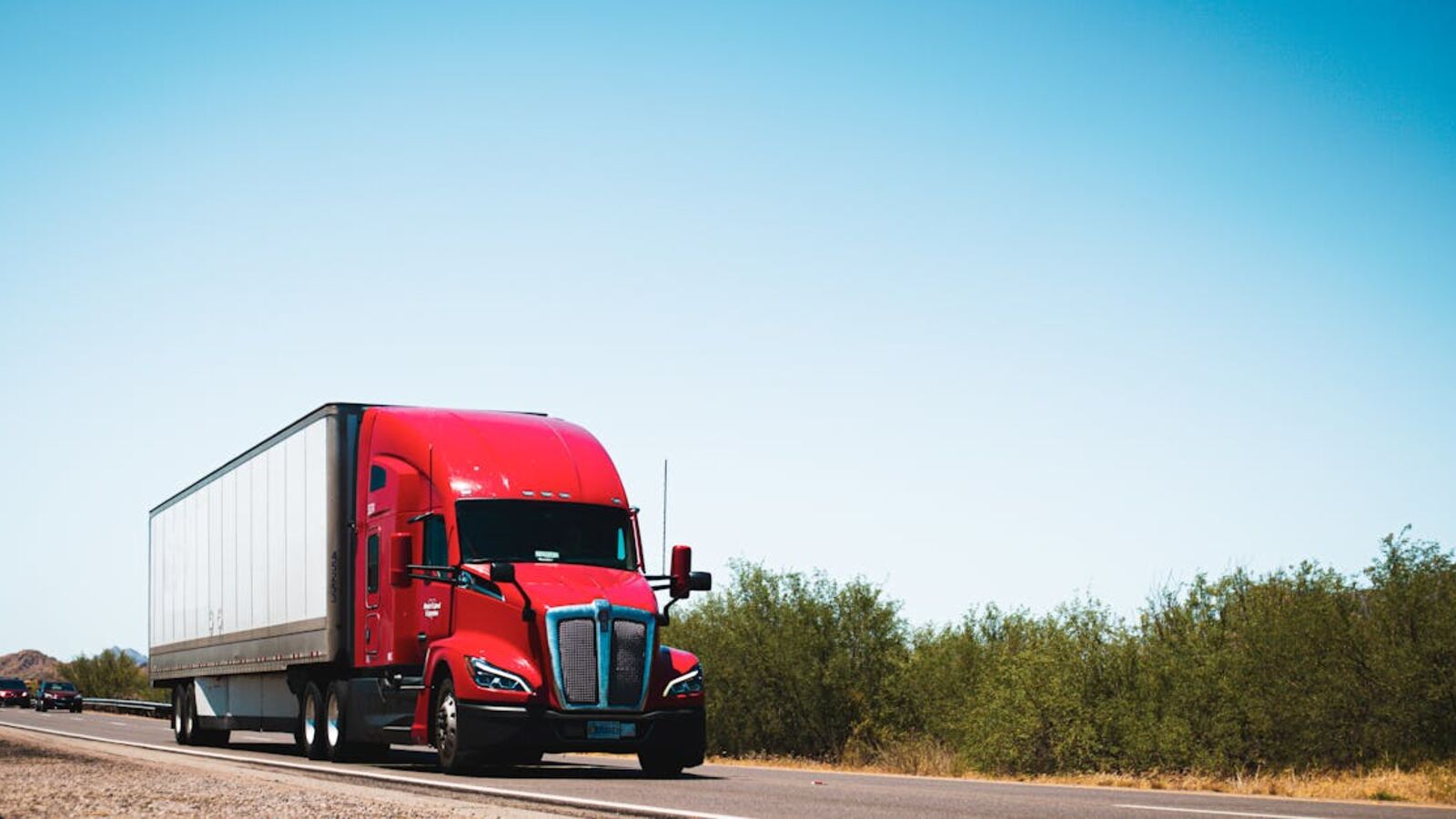 Кейс: продажа корпоративного транспорта в Санкт-Петербурге — Vibrant red semi-trailer truck driving on an open highway under a clear blue sky.