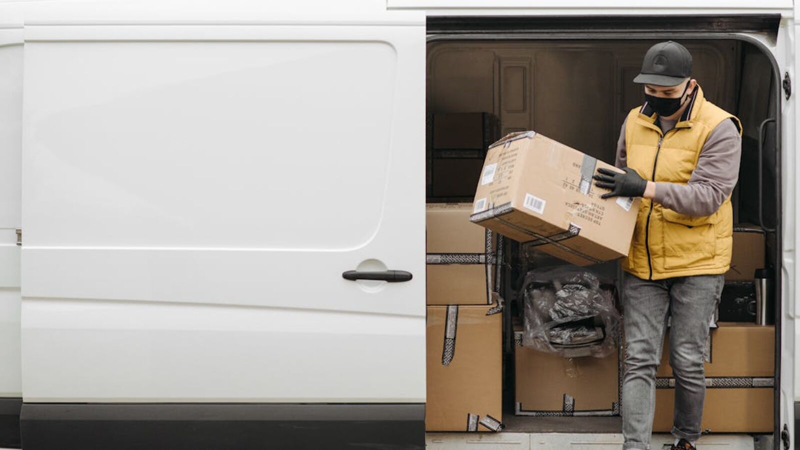 Кейс: продажа коммерческого фургона после активной эксплуатации в Санкт-Петербурге — Courier wearing mask unloads packages from white delivery van during the day.