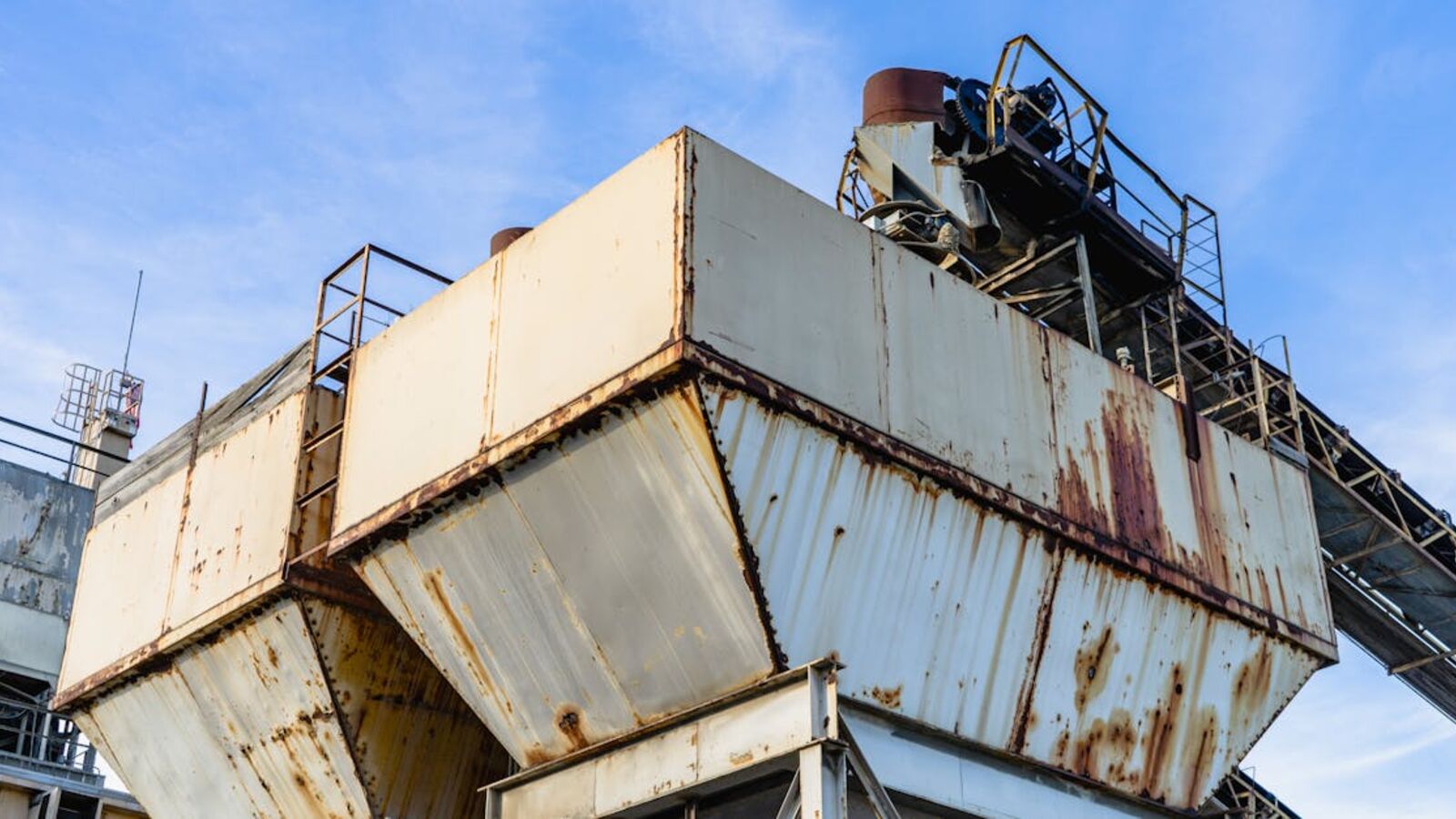 Close-up of rusty industrial equipment against a clear blue sky.