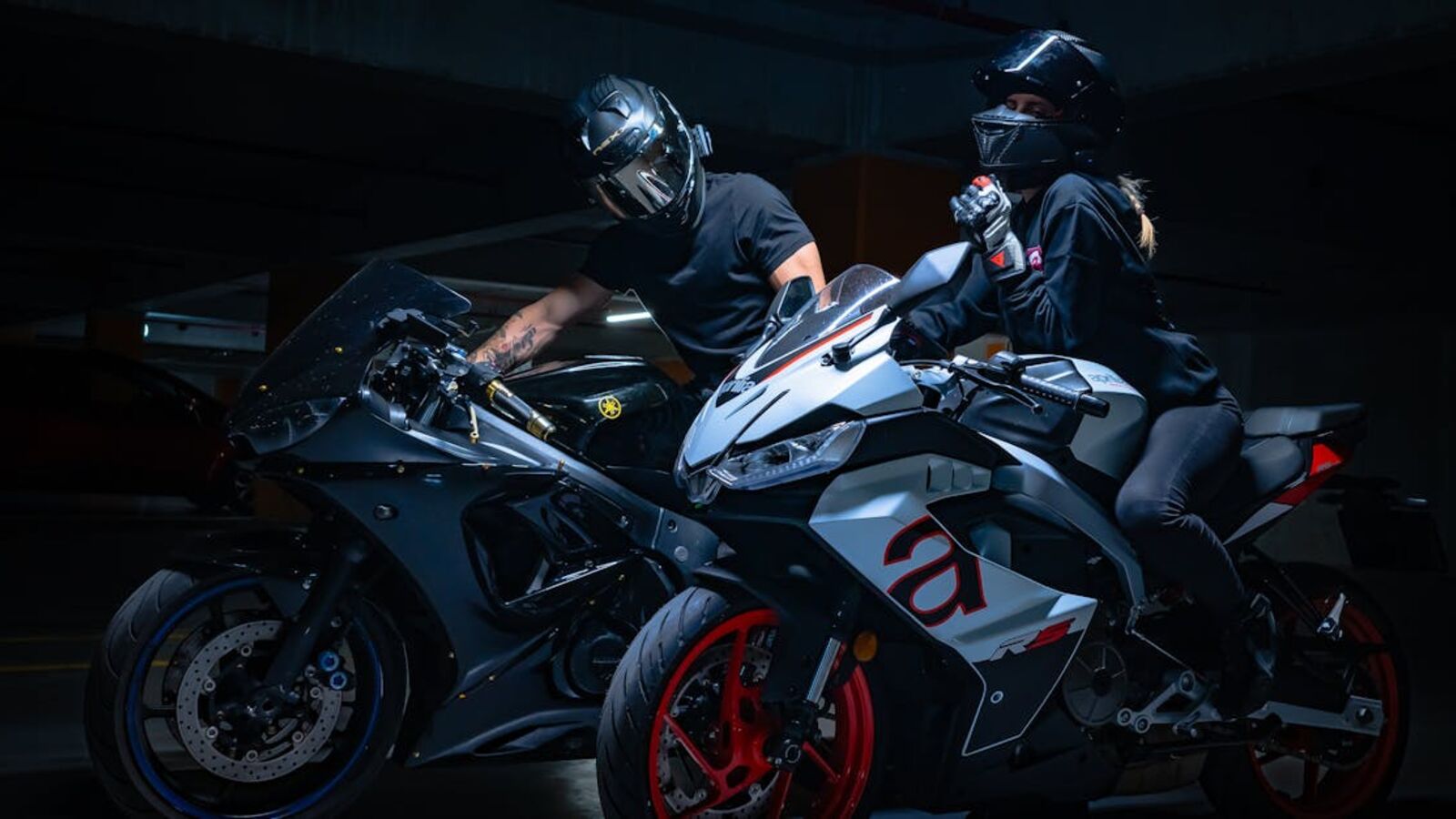 Кейс: продажа премиального мотоцикла в Санкт-Петербурге — Two motorcyclists in helmets pose on sports bikes in a dimly lit garage.