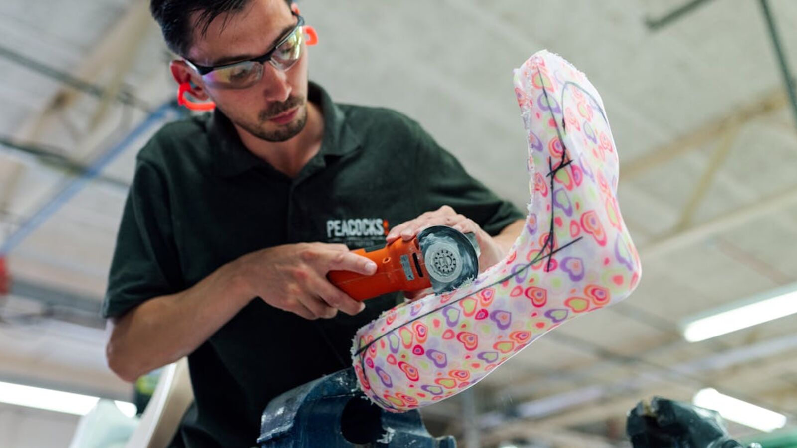 Кейс: продажа нишевого оборудования с узким рынком в Санкт-Петербурге — Orthotic technician using power tool to craft a colorful ankle foot orthosis in a workshop.