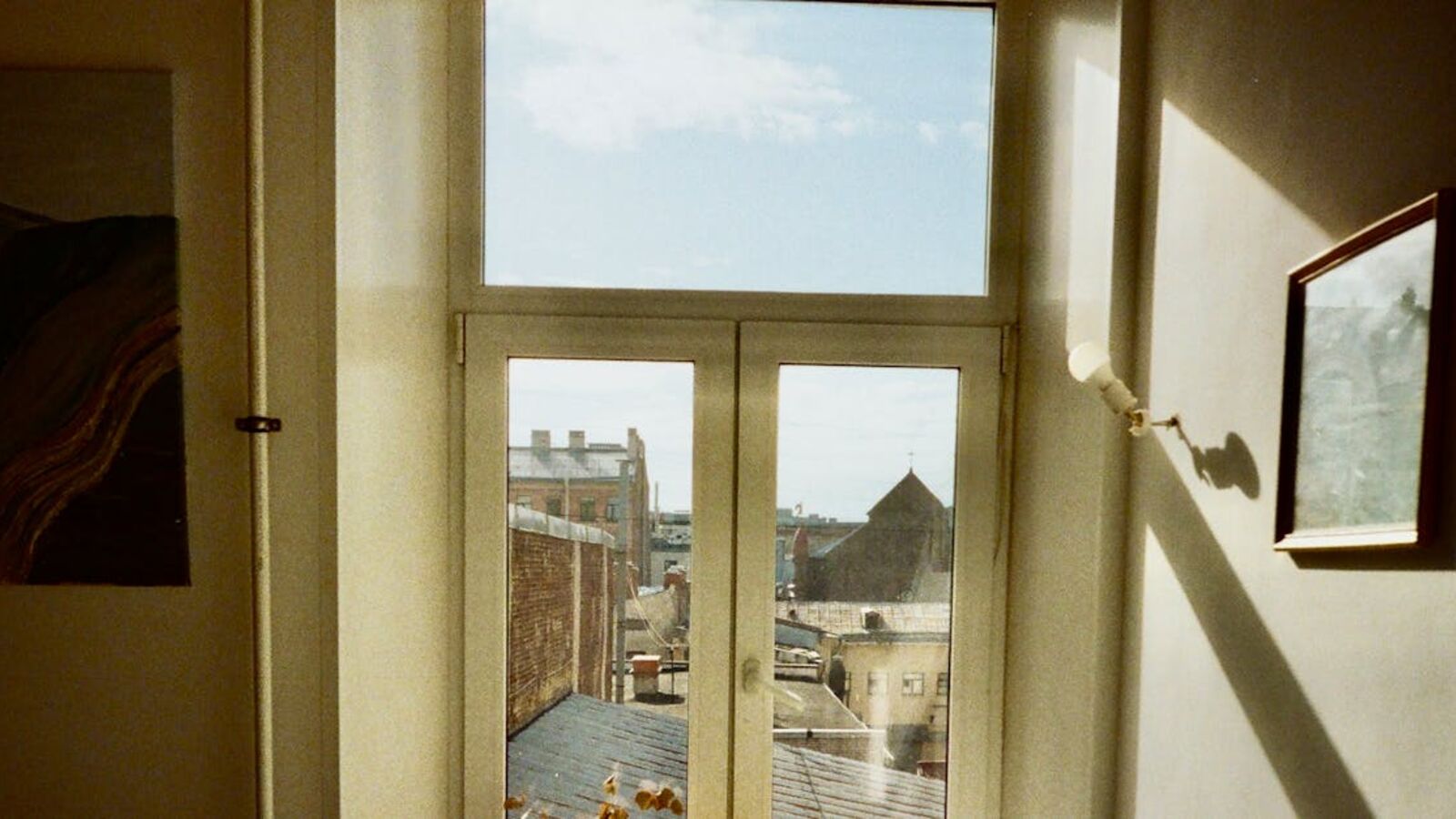 Кейс: продажа апартамента со слабой ликвидностью в Санкт-Петербурге — Warm indoor scene capturing a window view of Saint Petersburg's architecture and rooftops under a blue sky.