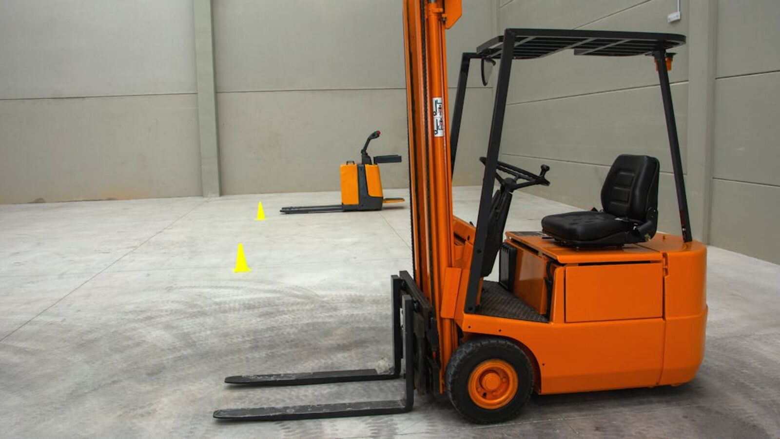 Кейс: продажа фронтального погрузчика XCMG в Санкт-Петербурге — An orange forklift in a spacious warehouse with concrete floors and minimal equipment.