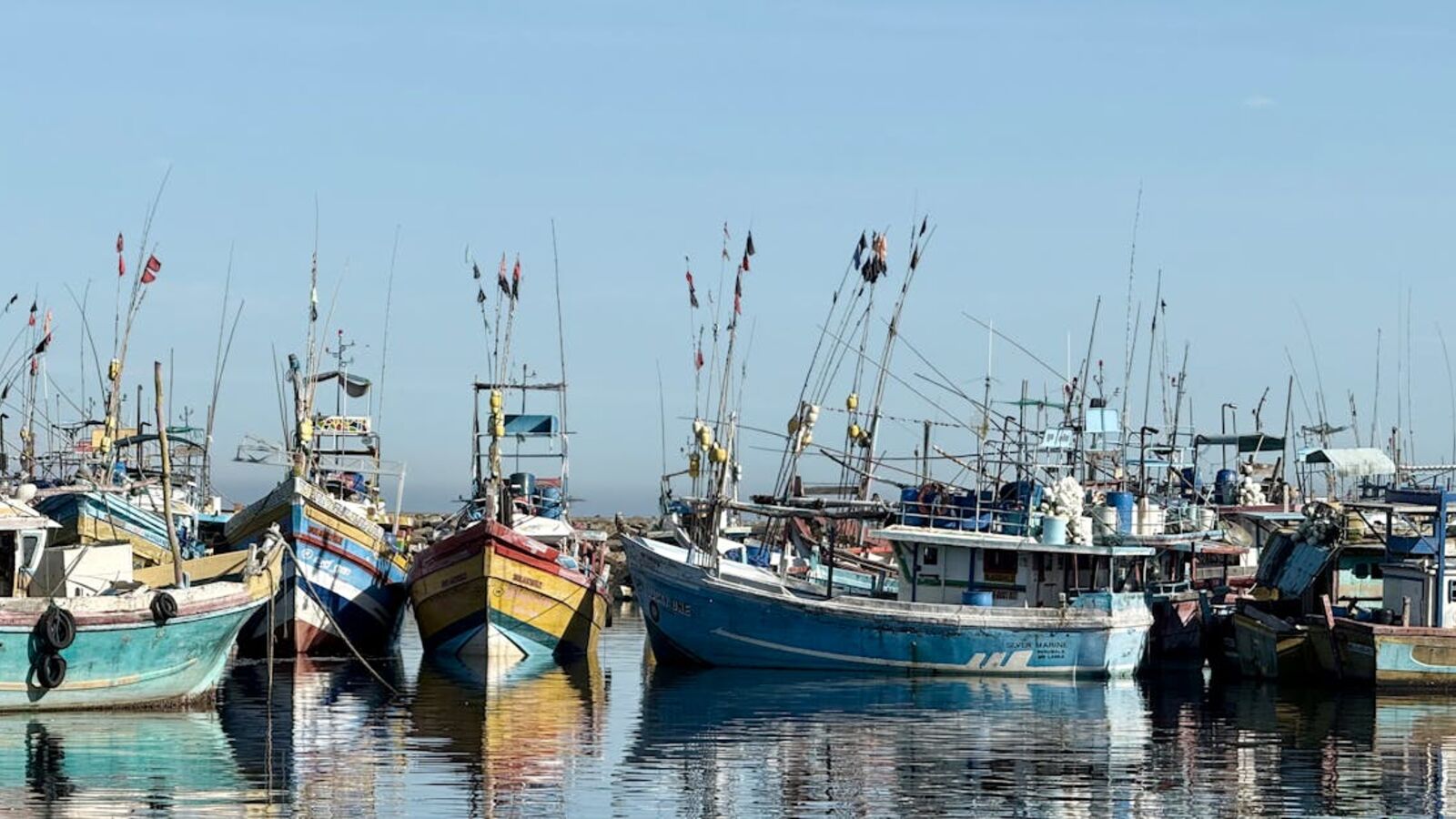 Кейс: продажа комплекта лодка + мотор в Санкт-Петербурге — Docked fishing boats at a harbor reflecting on still waters under a blue sky.