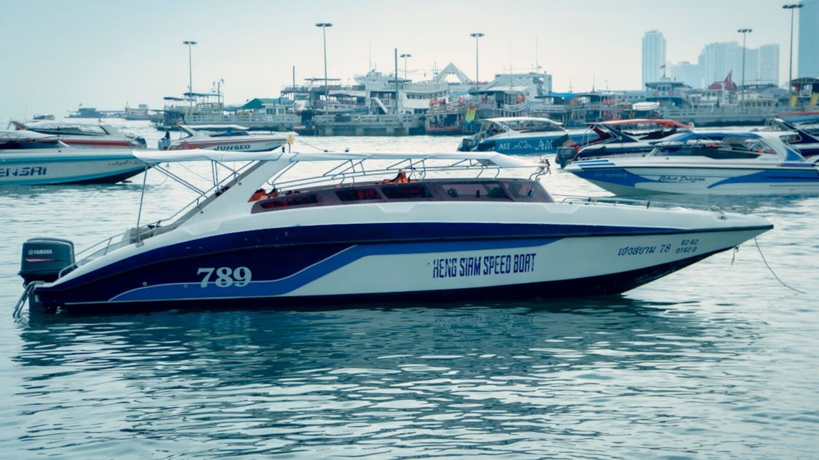 Кейс: продажа коммерческого маломерного судна в Санкт-Петербурге — A speedboat moored in a busy marina, surrounded by other boats with a cityscape in the background.