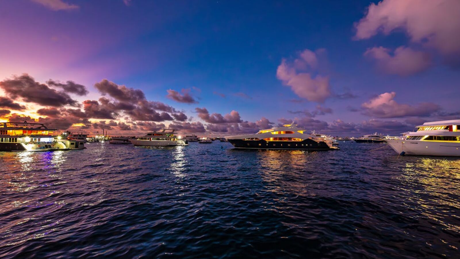 Кейс: продажа моторной яхты с узким спросом в Санкт-Петербурге — A serene sunset view of luxury yachts anchored in the Maldives, reflecting vibrant colors on the water.